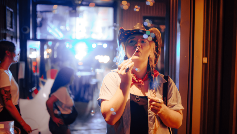 Woman in cowboy hat blowing bubbles