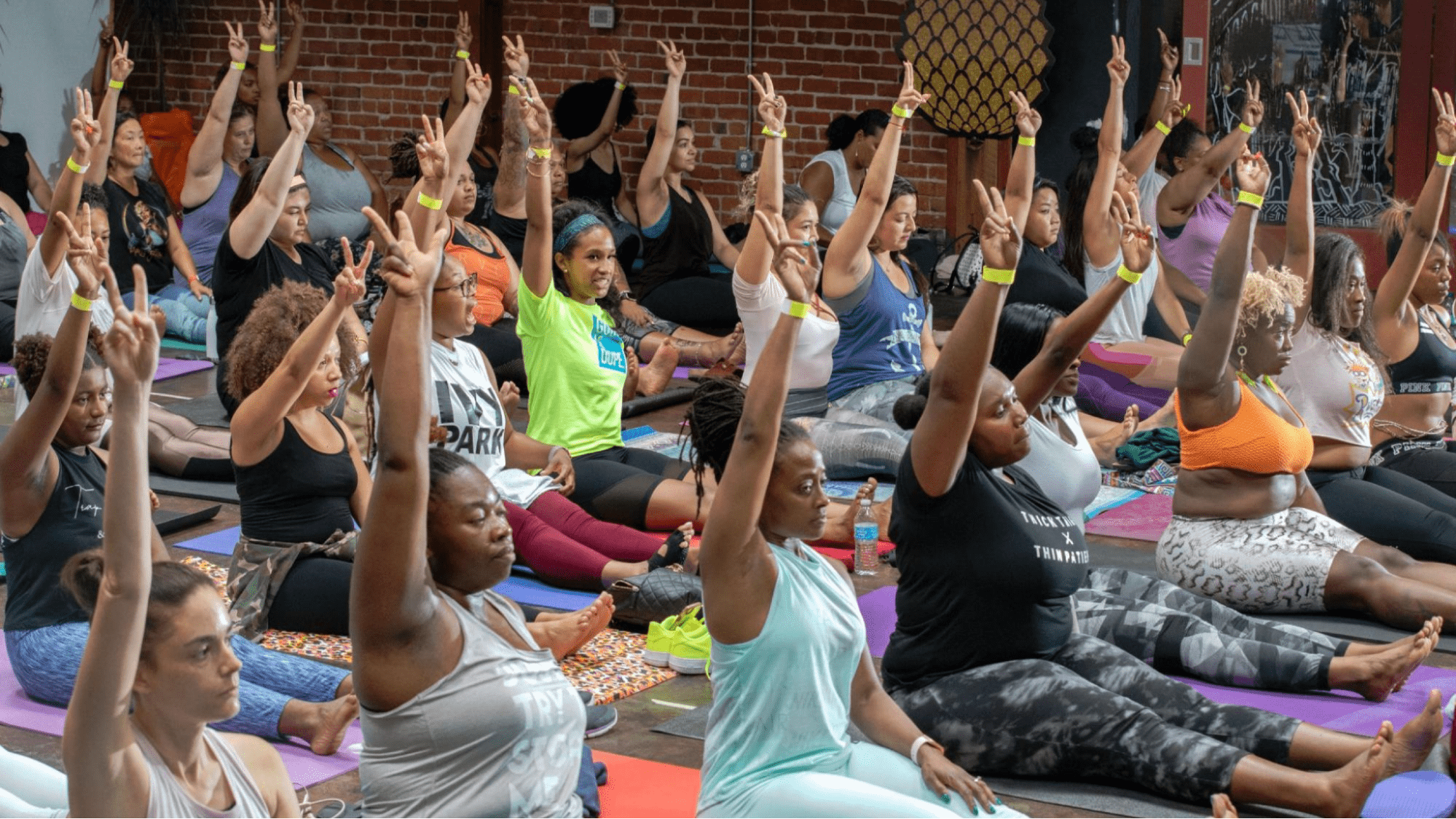 Engaged audience raises their hands at a yoga event.
