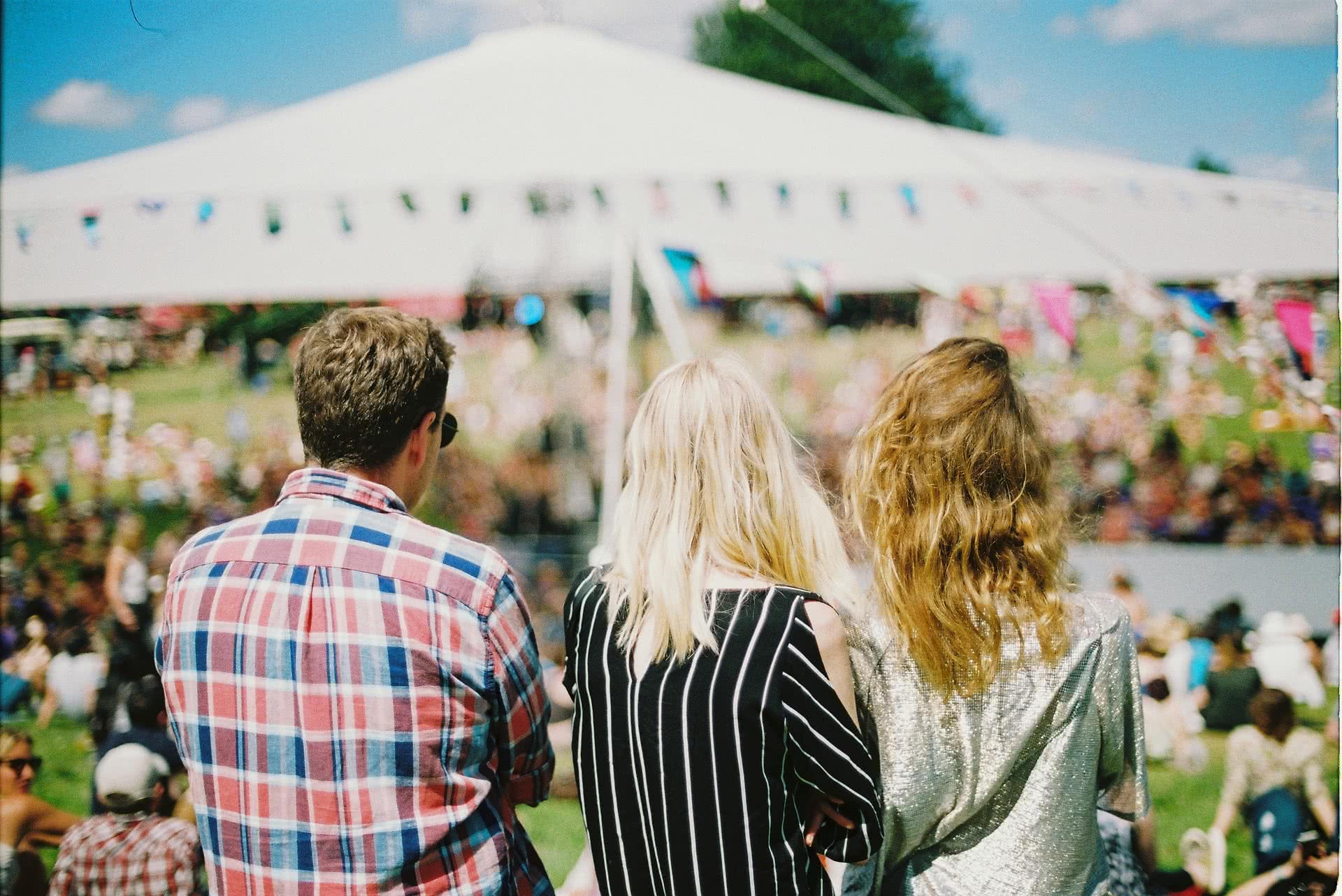 An image of three people facing away from the camera at a festival.