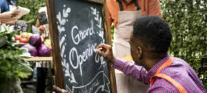 man writing Grand Opening on chalkboard