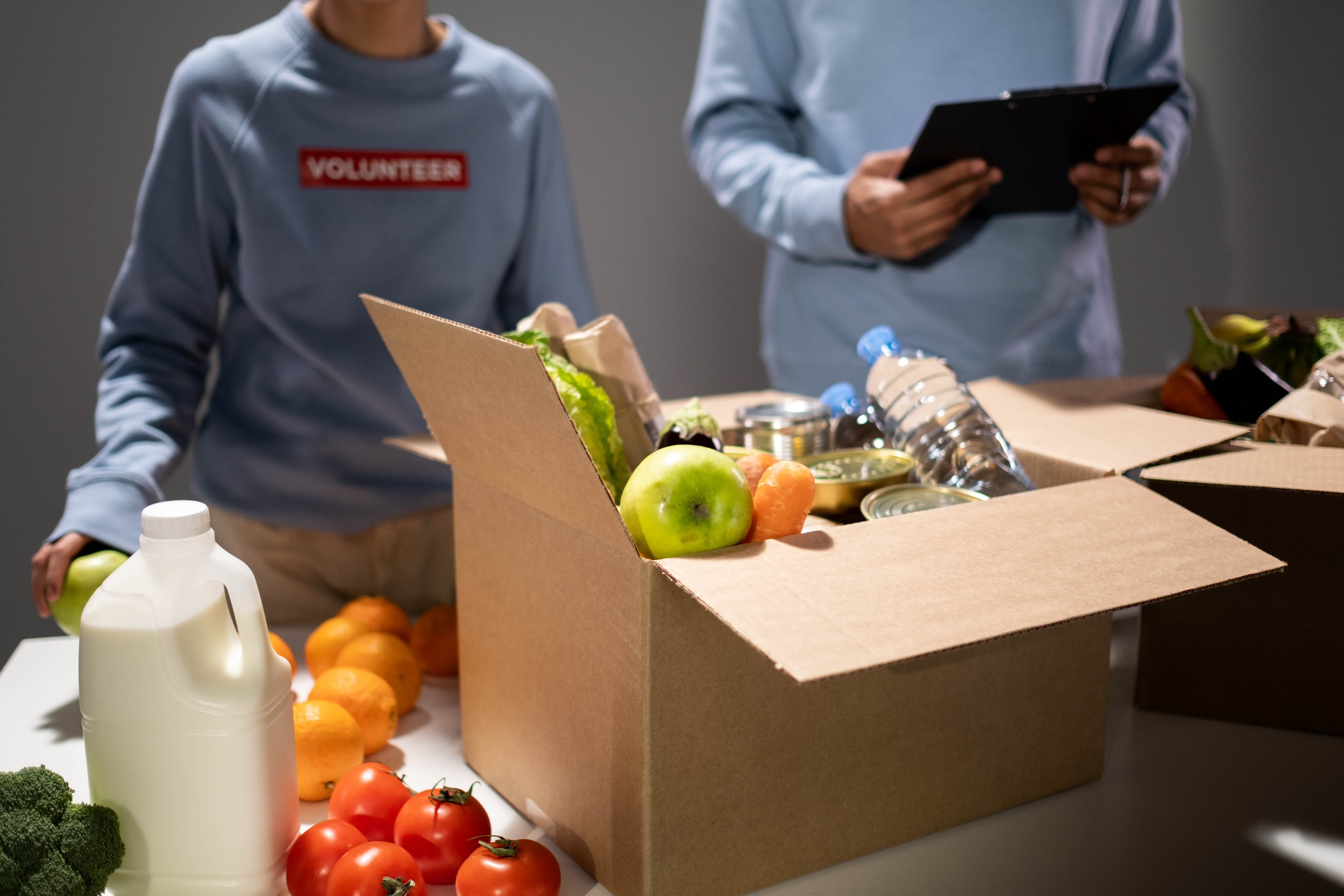 People packing a box with food.