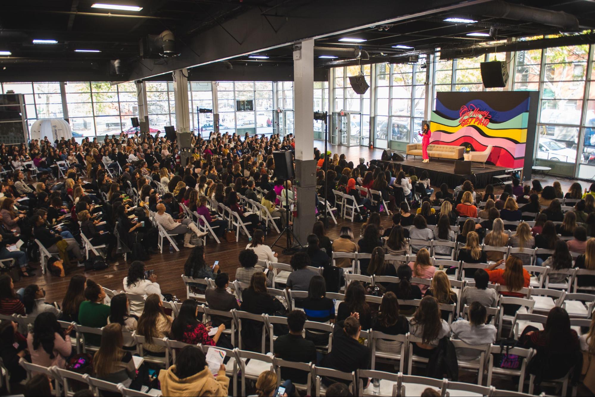 A woman speaking in front of a large conference audience