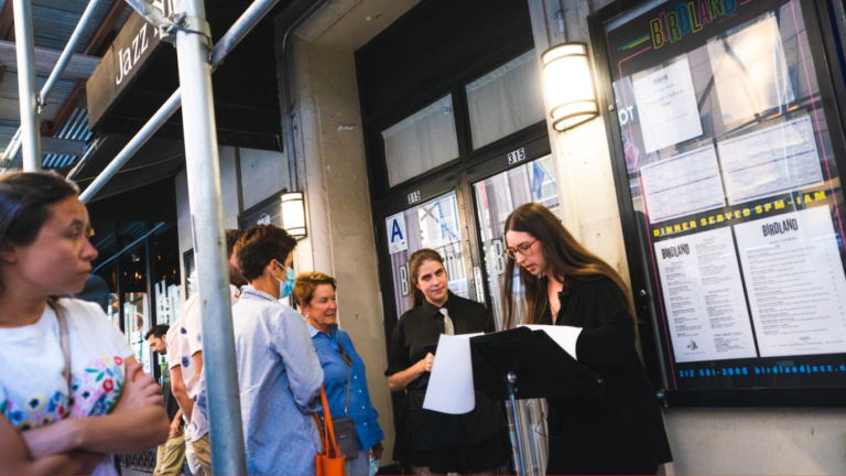 Event staff speak to guests outside of an event venue