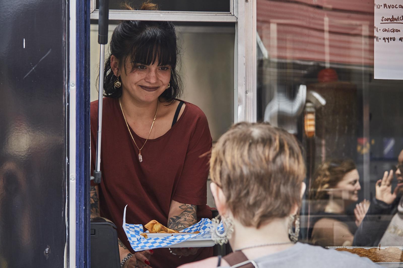Food truck worker hands dish to customer at Avocadocon