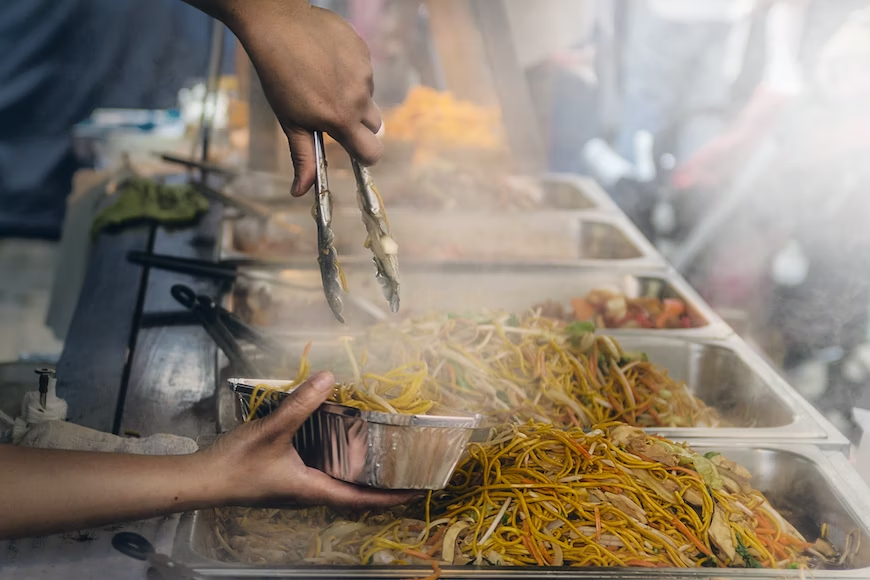 Food truck worker portioning stirfry