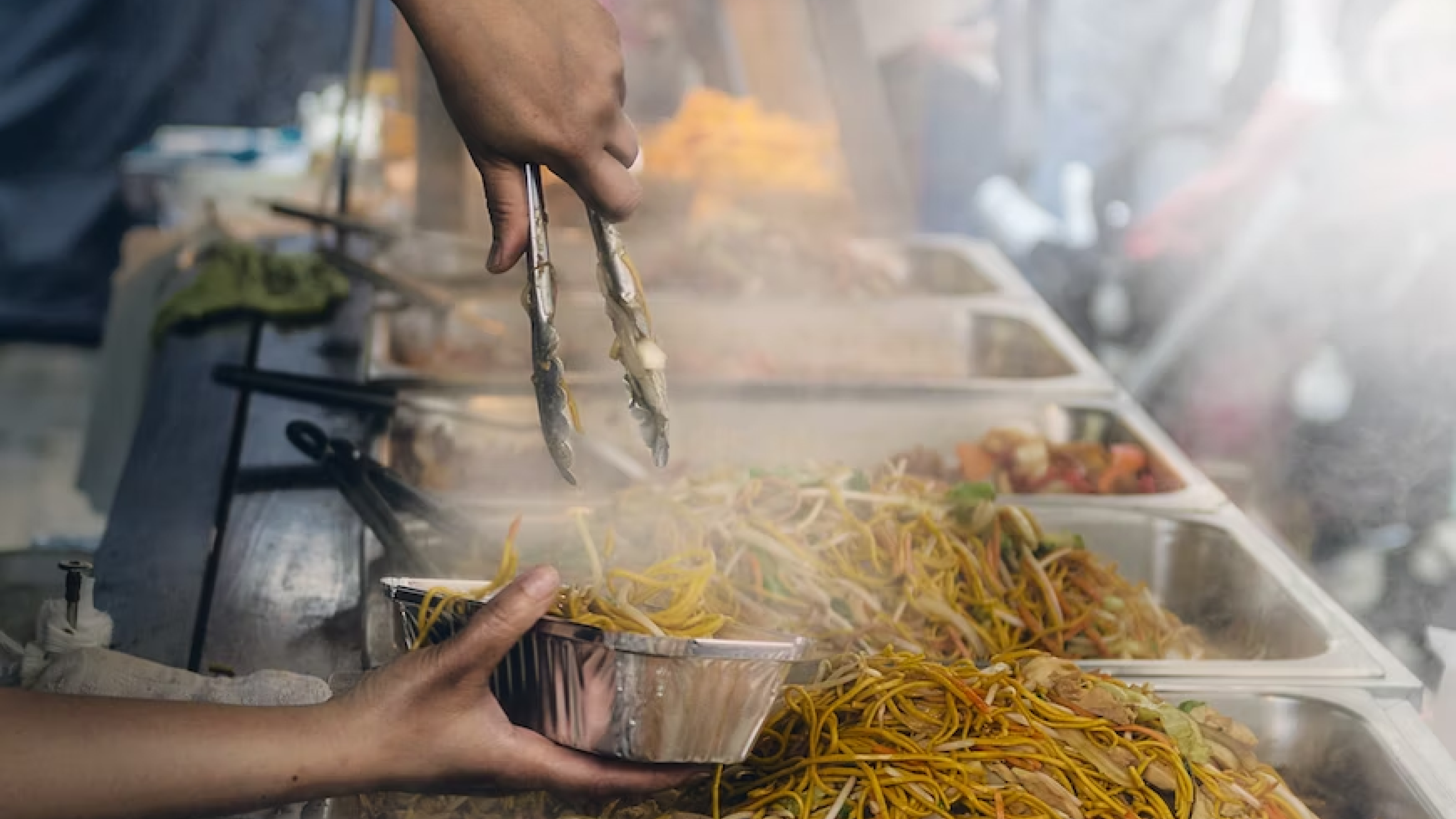 Food truck worker portioning stirfry