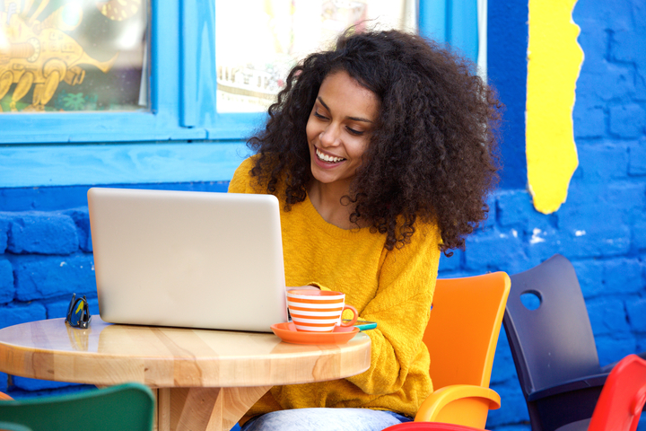 Women excitedly reads from laptop at a table