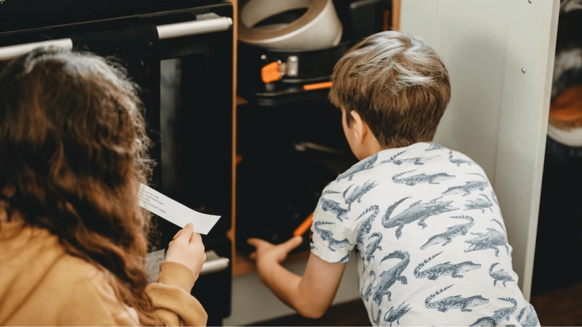 Two children find scavenger hunt clue in cupboard