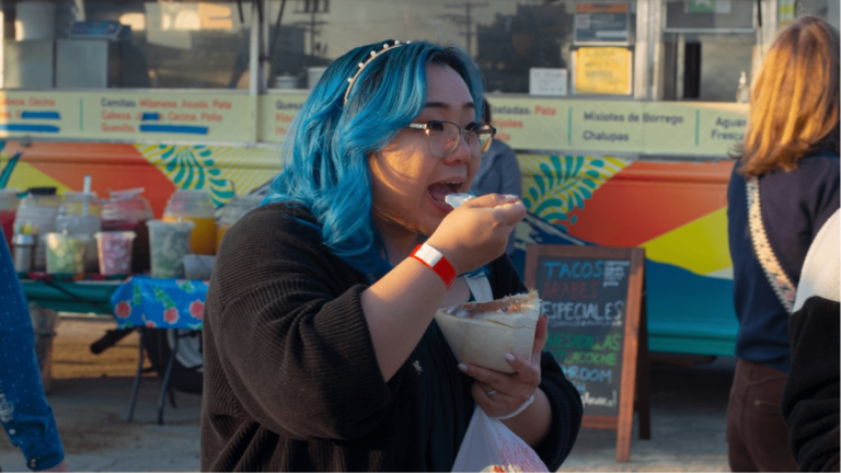 A person eating in front of a food truck