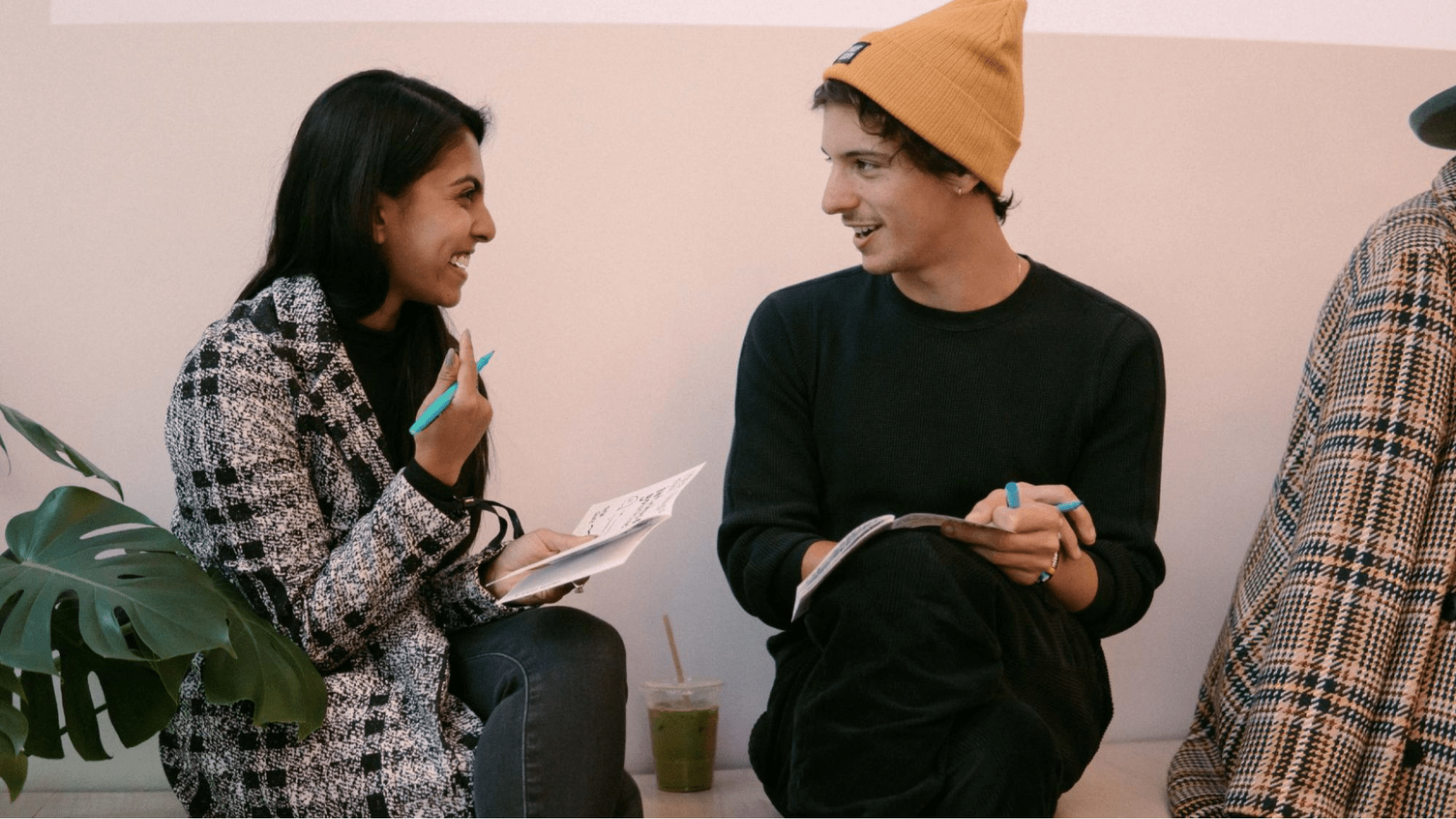 Two people talking and laughing with notebooks