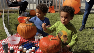 Two kids painting pumpkins