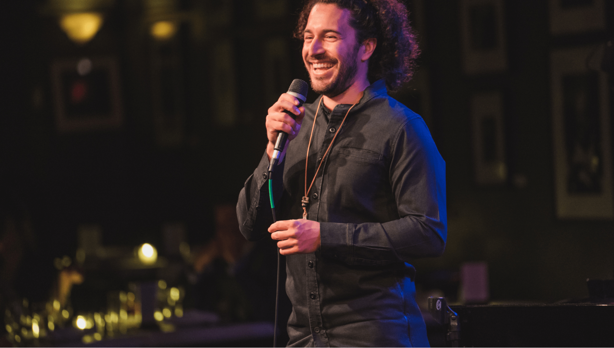 Man stands on stage smiling while talking into mic
