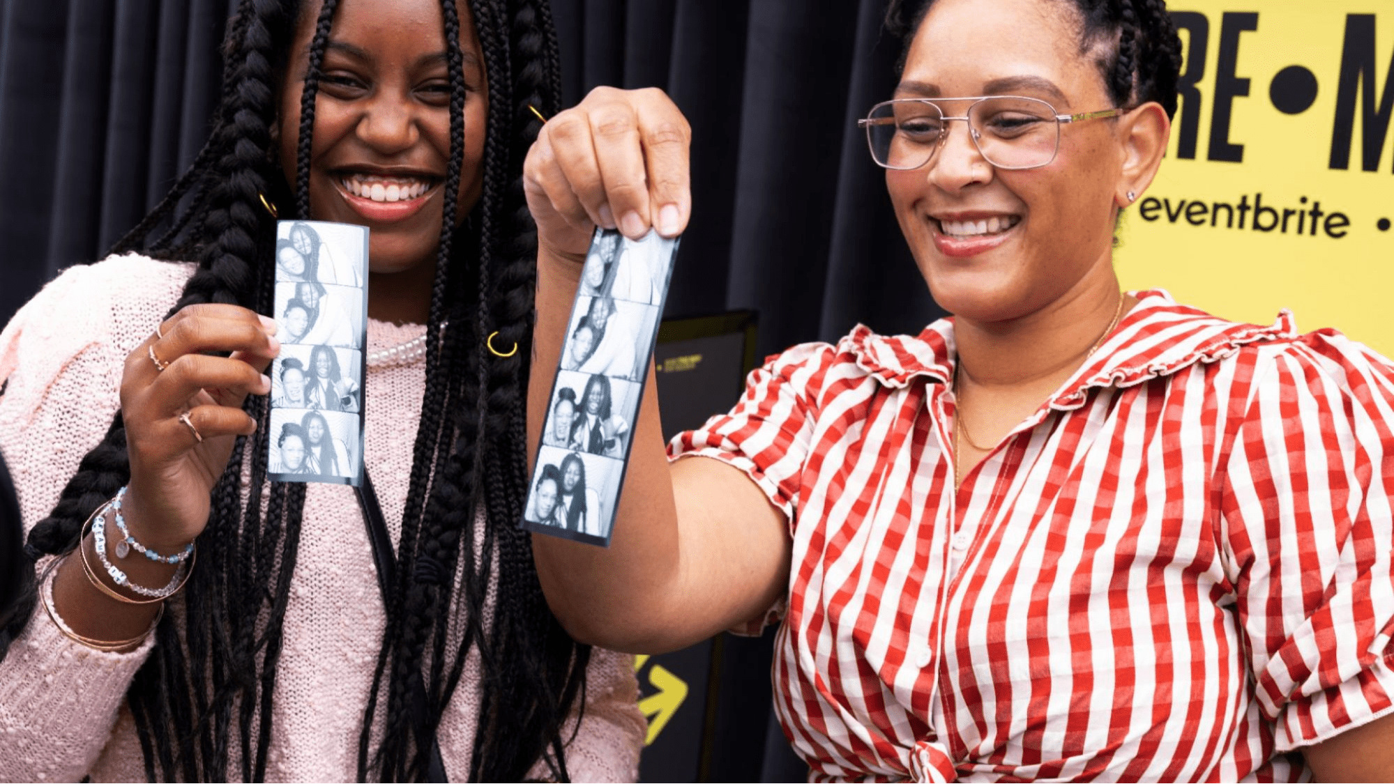 Two event attendees smile holding printed photos