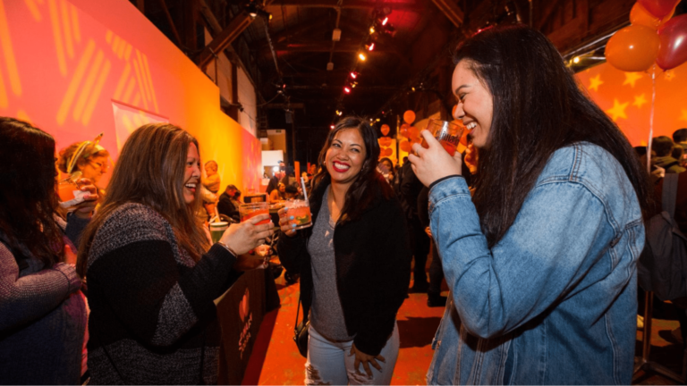 Three women smiling and drinking at an event