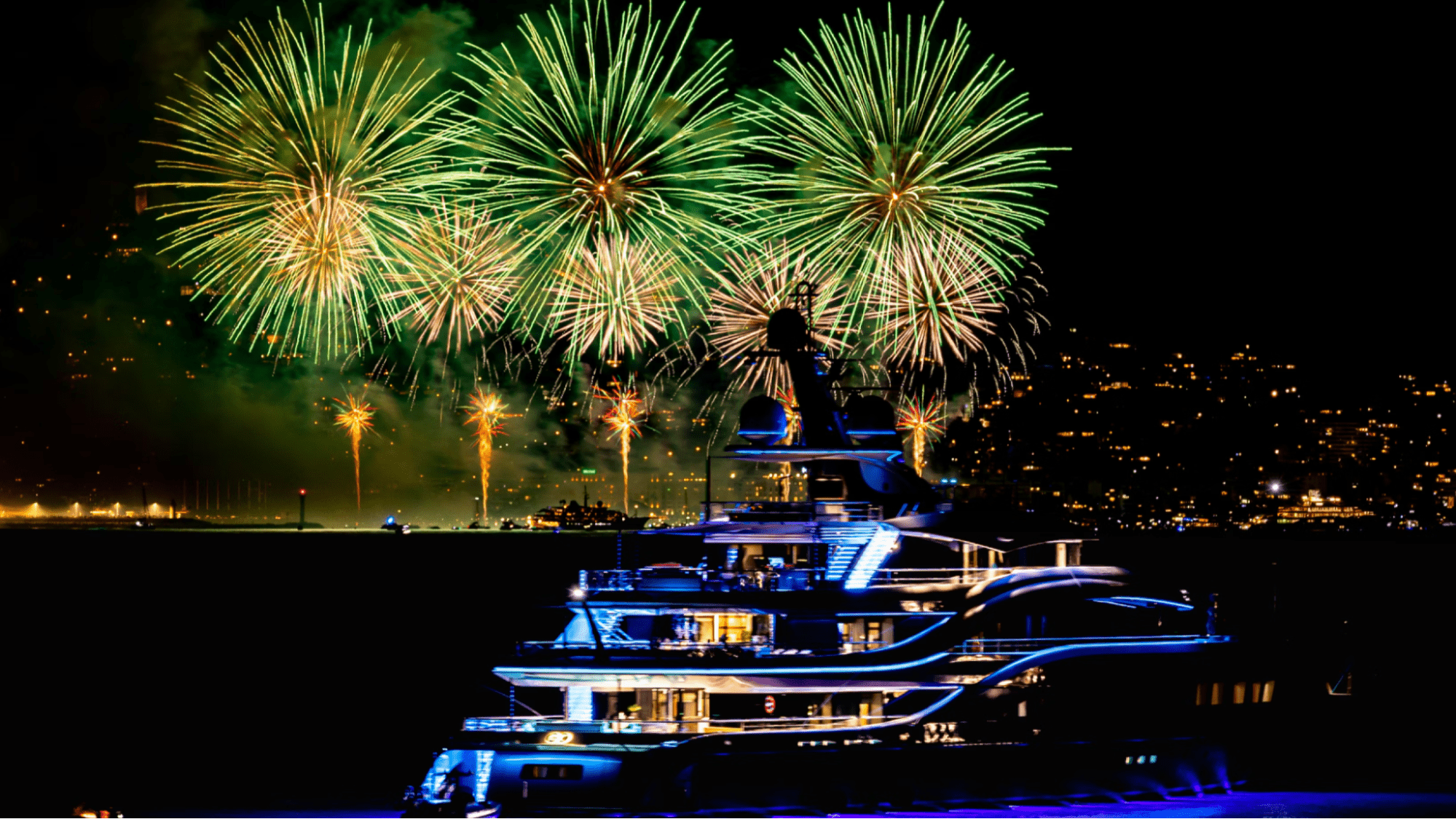 Yacht anchored in bay with fireworks in the background