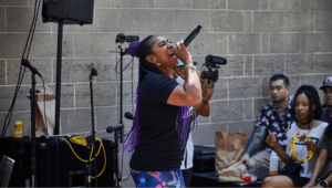 Woman singing in front of a crowd at an outdoor event