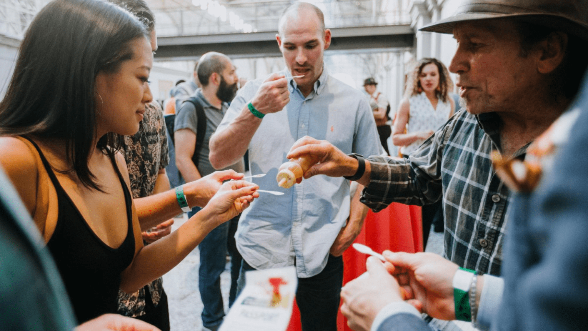 Event staff offers samples of sauce to event guests