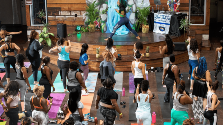 Yoga event organizer stands on stage leading a yoga event