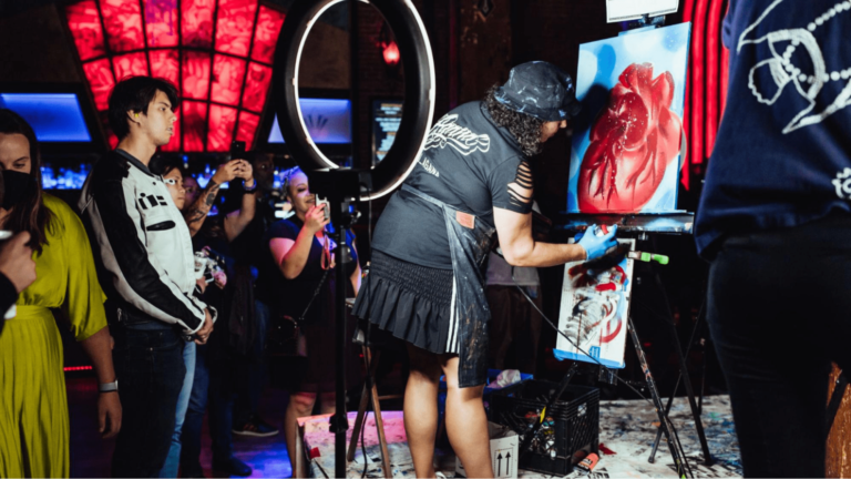 An artist creates a painting while being filmed for virtual event